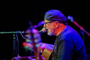 Side view of Wayne Jury singing and playing guitar at Geelong Arts Centre